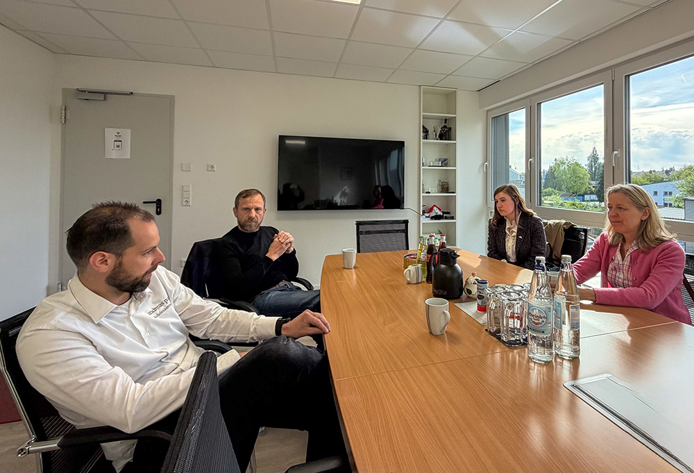 Je zwei Frauen und Männer sitzen an einem Konferenztisch und diskutieren